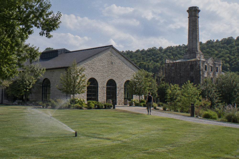 A bourbon distillery visitor center with limestone walls and green lawn under a Kentucky sky